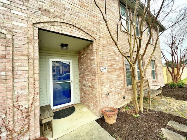 entrance to property with brick siding and fence