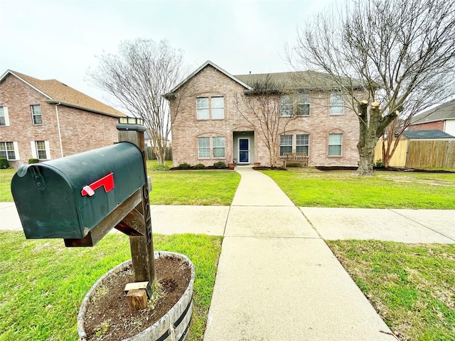 view of front of home with a front yard, brick siding, and fence