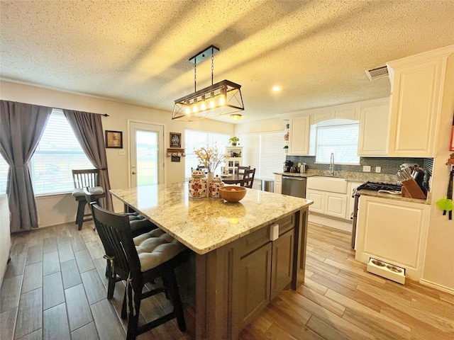 kitchen with white cabinets, stainless steel dishwasher, a center island, open shelves, and decorative light fixtures