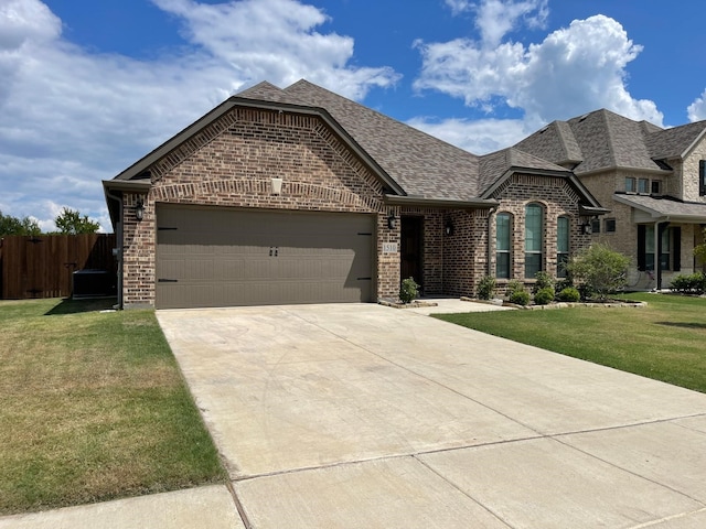 french country home with driveway, brick siding, a shingled roof, an attached garage, and a front yard