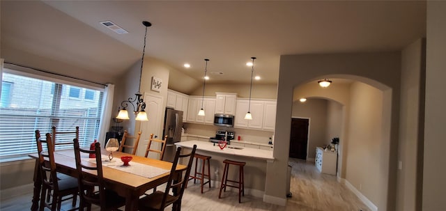 dining area with arched walkways, baseboards, visible vents, and light wood finished floors