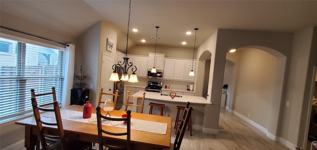 dining area with arched walkways, light wood-style flooring, baseboards, and recessed lighting