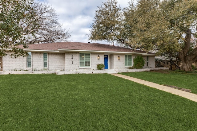 ranch-style house with brick siding, a front lawn, and roof with shingles