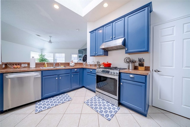 kitchen featuring a ceiling fan, appliances with stainless steel finishes, blue cabinets, under cabinet range hood, and a sink