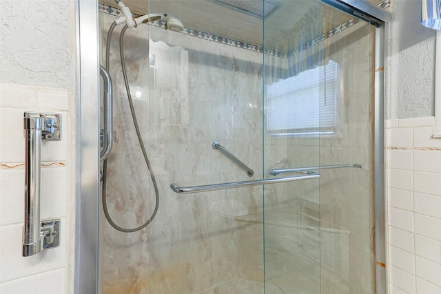 full bath featuring a stall shower, tile walls, and a textured wall