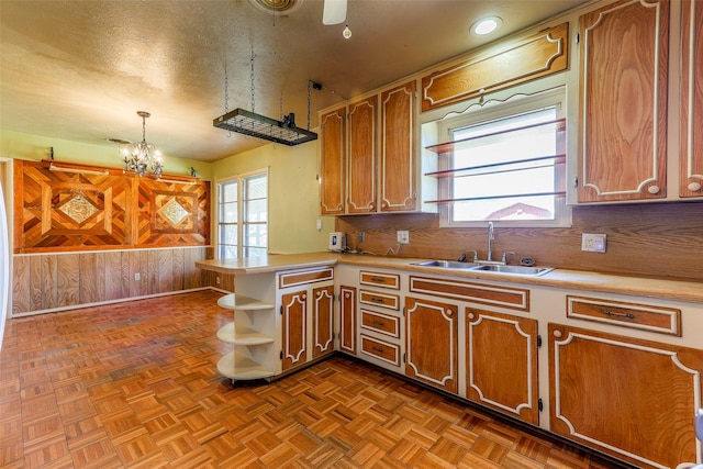 kitchen featuring open shelves, light countertops, decorative backsplash, brown cabinetry, and a sink