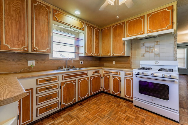 kitchen with tasteful backsplash, white gas range, light countertops, and a sink