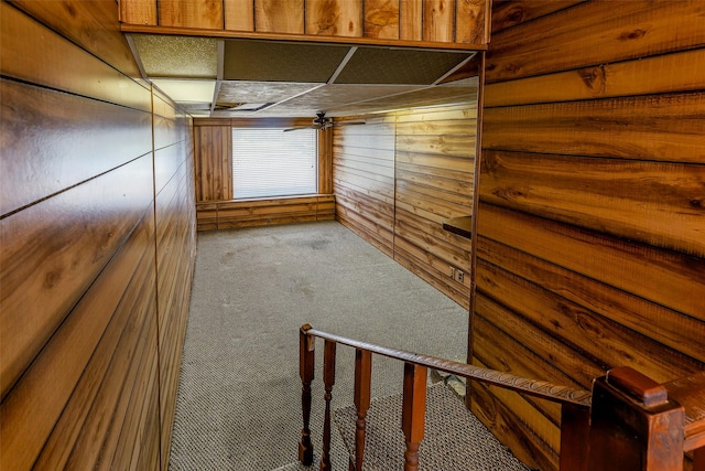 interior space featuring carpet, wooden walls, and a ceiling fan