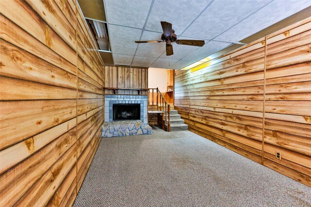 205 Bedford Ct E, Bedford, TX 76022 - unfurnished living room featuring carpet flooring, a tile fireplace, a ceiling fan, stairs, and wooden walls
