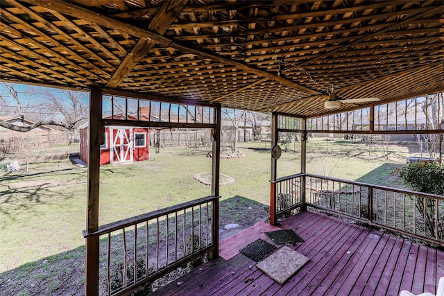 wooden terrace with an outdoor structure, a lawn, and a shed