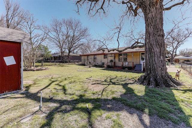 view of yard featuring a shed, a porch, an outdoor structure, and fence