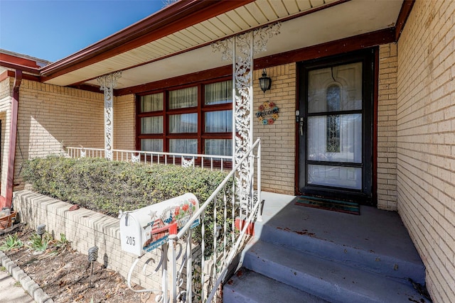 view of exterior entry with covered porch and brick siding