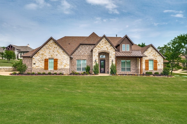 french country home featuring a standing seam roof, brick siding, metal roof, and a front yard