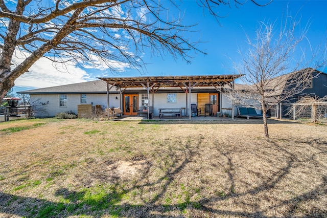 rear view of property with french doors, a lawn, and fence