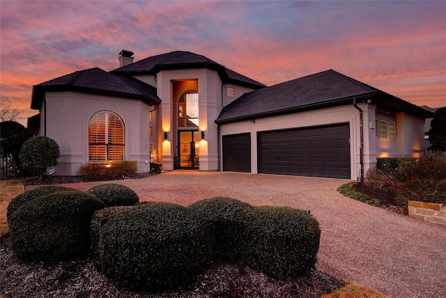 view of front of house featuring decorative driveway, a chimney, an attached garage, and stucco siding