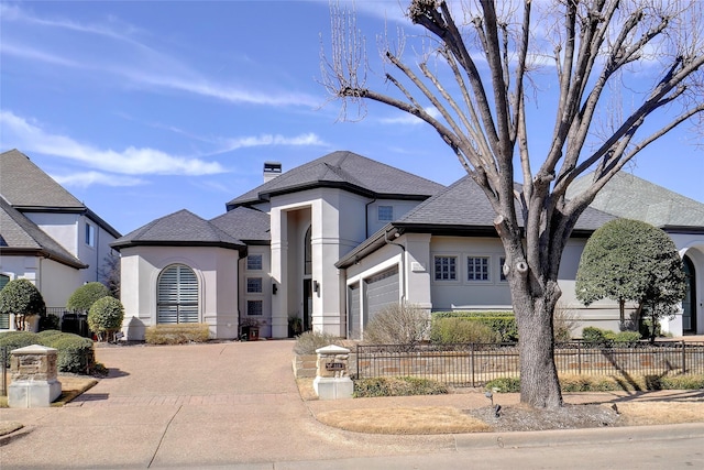 view of front of property featuring a garage, driveway, a fenced front yard, and stucco siding