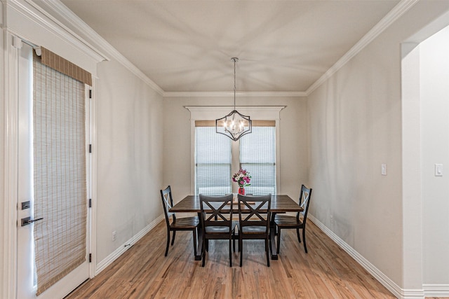 dining space with baseboards, ornamental molding, wood finished floors, and a notable chandelier