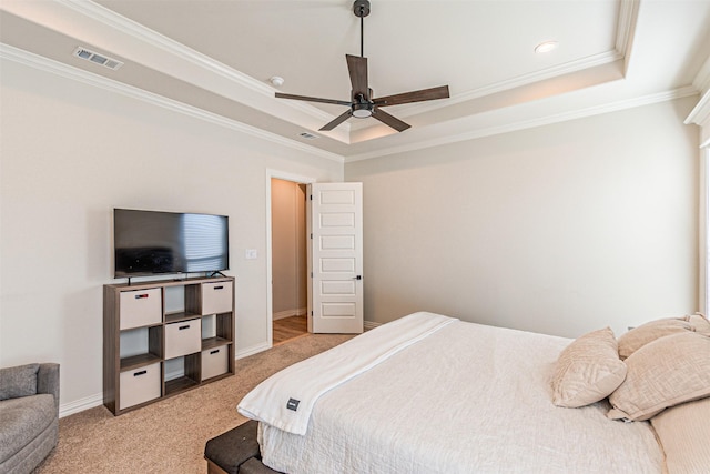 bedroom featuring light colored carpet, visible vents, baseboards, a tray ceiling, and crown molding