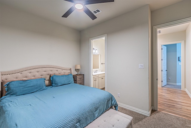 bedroom featuring visible vents, light carpet, a sink, ensuite bath, and baseboards