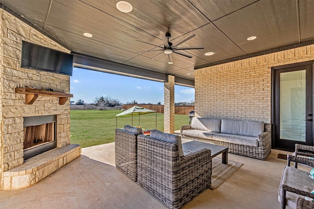 view of patio featuring an outdoor living space with a fireplace, fence, and ceiling fan