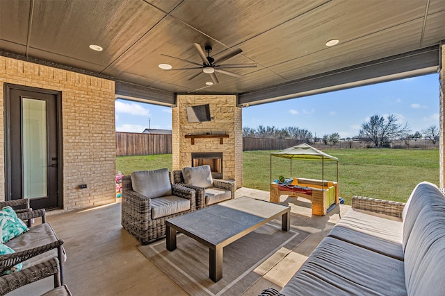 view of patio / terrace featuring ceiling fan, an outdoor living space with a fireplace, and fence