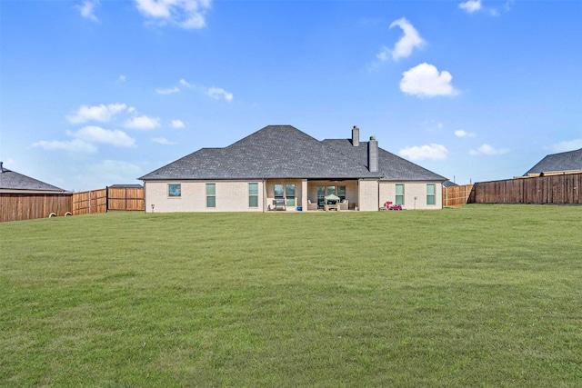 back of house featuring a patio area, a fenced backyard, a lawn, and a chimney