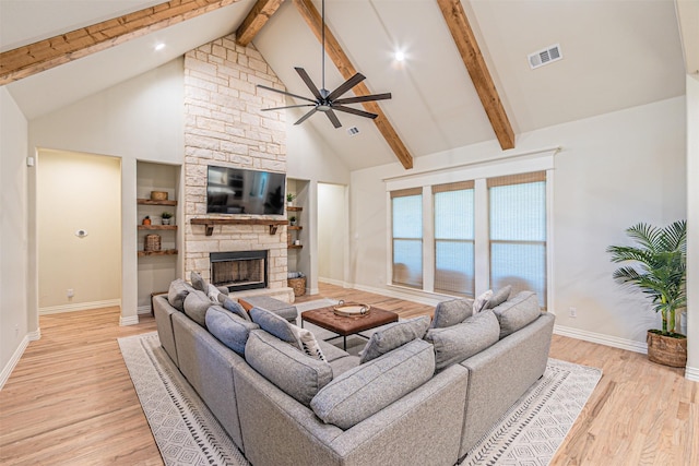 living area with visible vents, light wood-style flooring, a fireplace, high vaulted ceiling, and beam ceiling