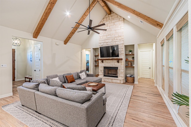 living area with a ceiling fan, light wood-style flooring, a fireplace, high vaulted ceiling, and beam ceiling