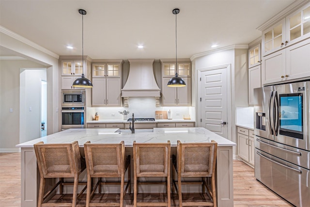 kitchen with custom range hood, appliances with stainless steel finishes, and a center island with sink