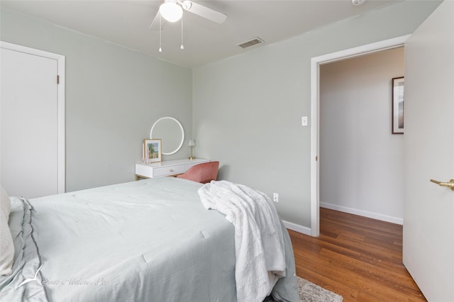 bedroom featuring dark wood-style floors, visible vents, baseboards, and a ceiling fan