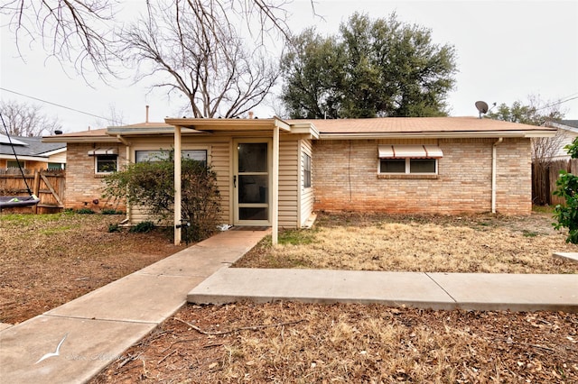 ranch-style house featuring brick siding and fence