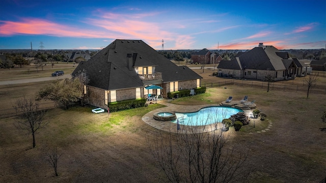 pool at dusk with a patio area, a fenced backyard, and a pool with connected hot tub