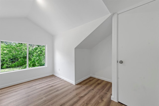 bonus room with lofted ceiling, light wood-type flooring, and baseboards