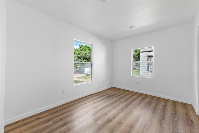 empty room with light wood-type flooring, a wealth of natural light, and baseboards