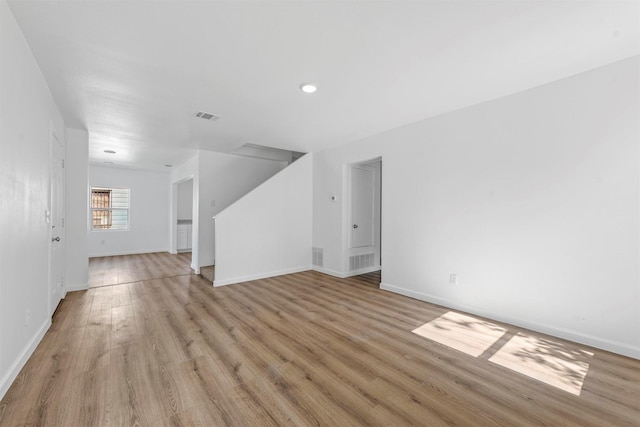 unfurnished living room with light wood-style flooring, visible vents, and baseboards