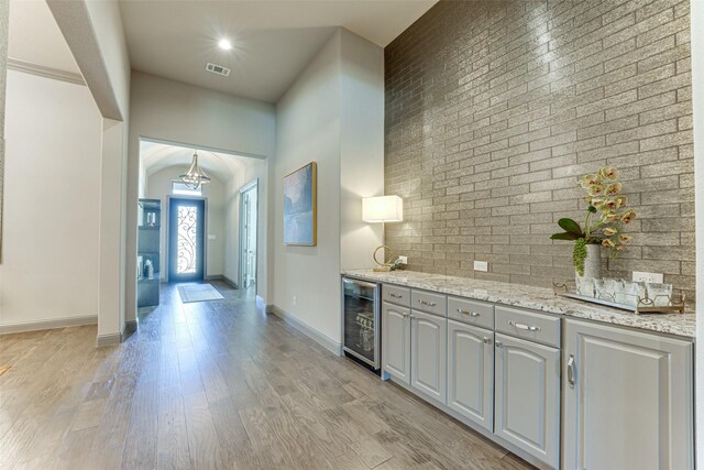 326 Prairie View Rd, Rockwall, TX 75087 - bar with visible vents, an inviting chandelier, brick wall, light wood-type flooring, and beverage cooler