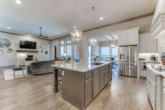 326 Prairie View Rd, Rockwall, TX 75087 - kitchen with ceiling fan with notable chandelier, a fireplace, ornamental molding, a sink, and stainless steel fridge
