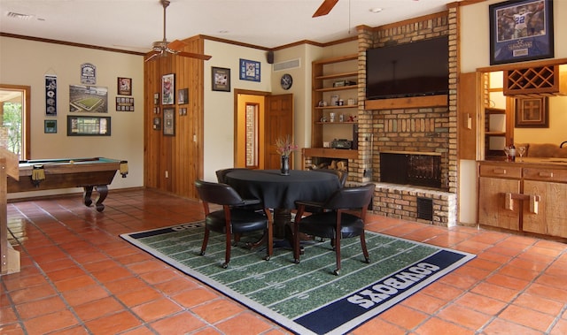 dining area with ceiling fan, tile patterned flooring, a fireplace, visible vents, and crown molding