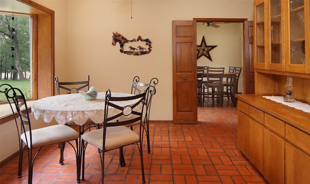 dining area featuring ceiling fan, brick floor, and baseboards