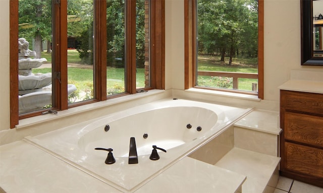 bathroom featuring tile patterned flooring, a jetted tub, and vanity