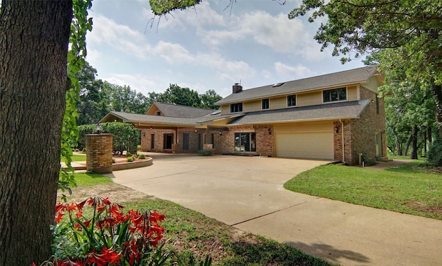 traditional-style home with a garage, brick siding, driveway, a chimney, and a front yard