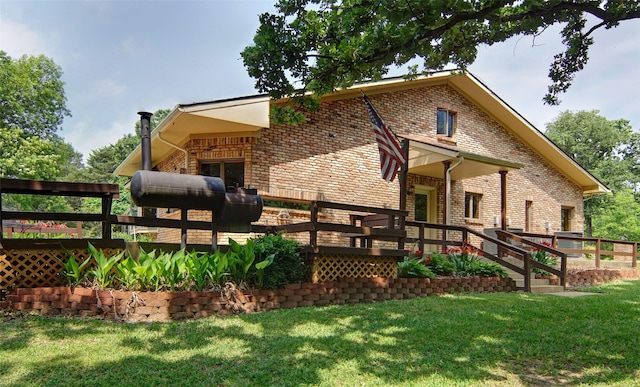 rear view of house with brick siding, a lawn, and a wooden deck