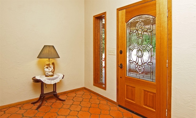 foyer entrance with a textured wall and baseboards