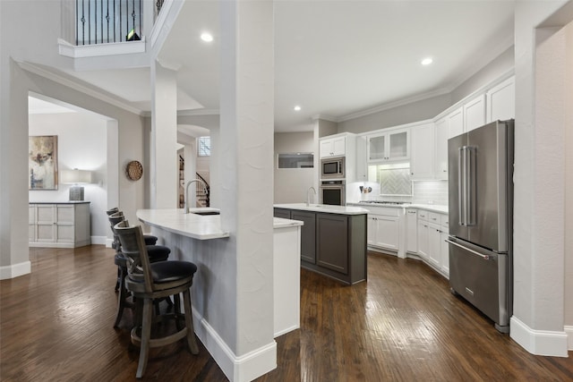 kitchen featuring white cabinets, glass insert cabinets, stainless steel appliances, light countertops, and a sink