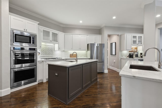 kitchen featuring glass insert cabinets, white cabinets, a sink, and appliances with stainless steel finishes