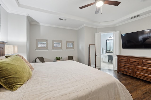 bedroom featuring ornamental molding, a tray ceiling, wood finished floors, and visible vents