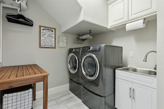 laundry area with washer and dryer, cabinet space, a sink, and baseboards