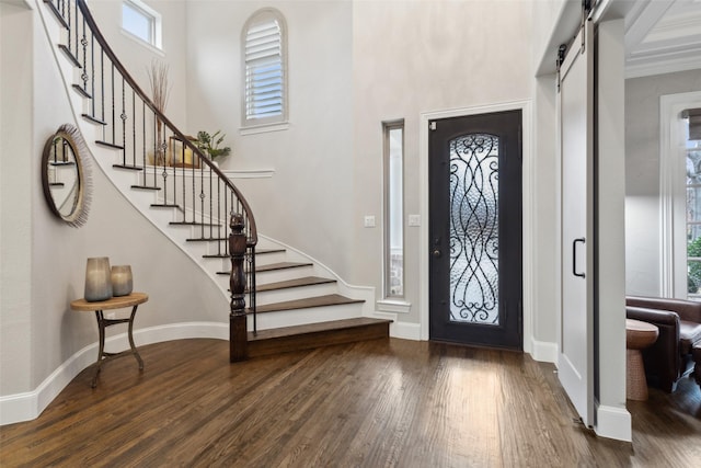 foyer entrance with a barn door, dark wood-style flooring, a wealth of natural light, and baseboards