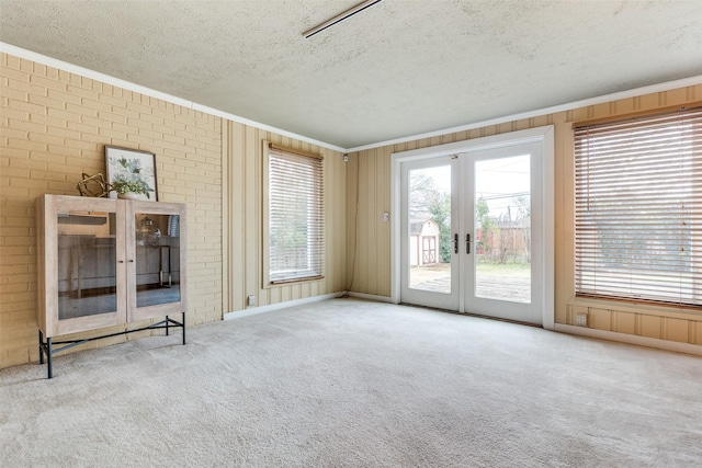 430 Mayrant Dr, Dallas, TX 75224 - unfurnished living room featuring french doors, ornamental molding, a textured ceiling, brick wall, and carpet