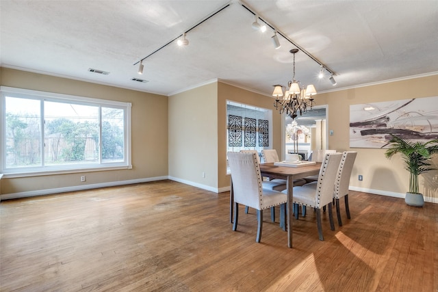 430 Mayrant Dr, Dallas, TX 75224 - dining room featuring rail lighting, a chandelier, baseboards, crown molding, and wood finished floors